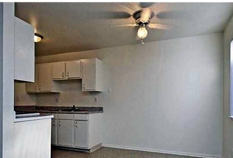 A kitchen with white cabinets and a ceiling fan.