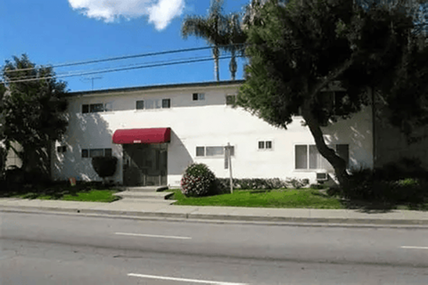 A white building with a red awning sits on the corner of a street.
