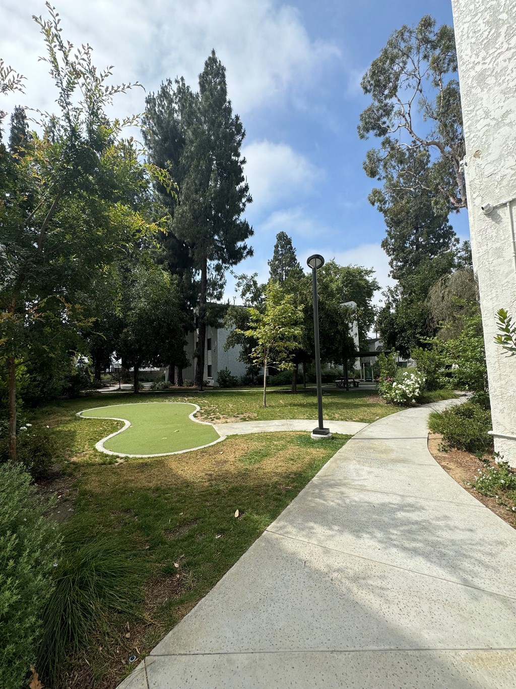 a sidewalk with a golf area and a grass courtyard