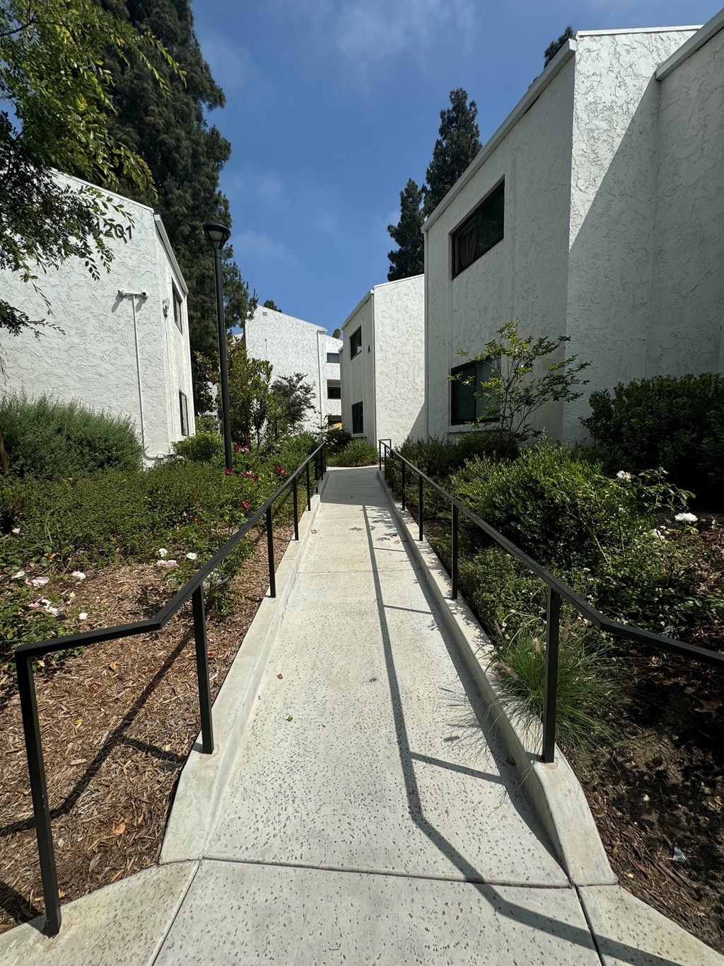 a path between two buildings with black railings