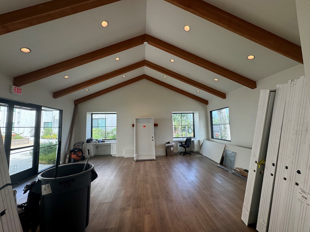 a club room with a vaulted ceiling and wood floors