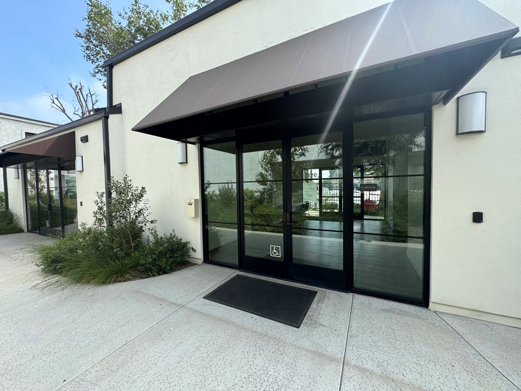 the front entrance of a white building with glass doors