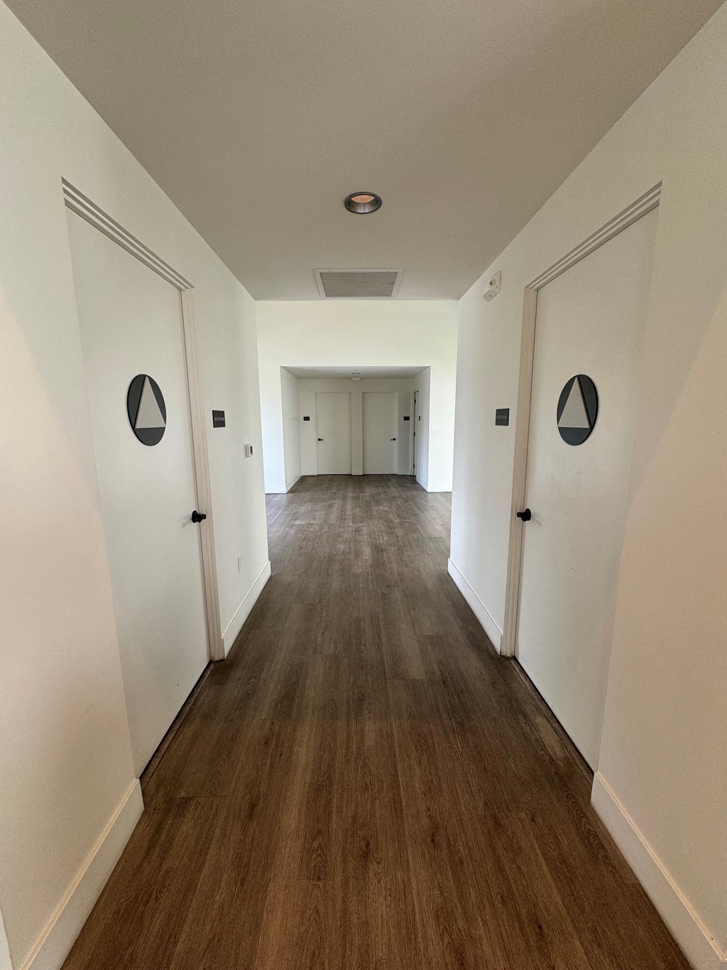 a look down a hallway in the club room with white walls and wood floors