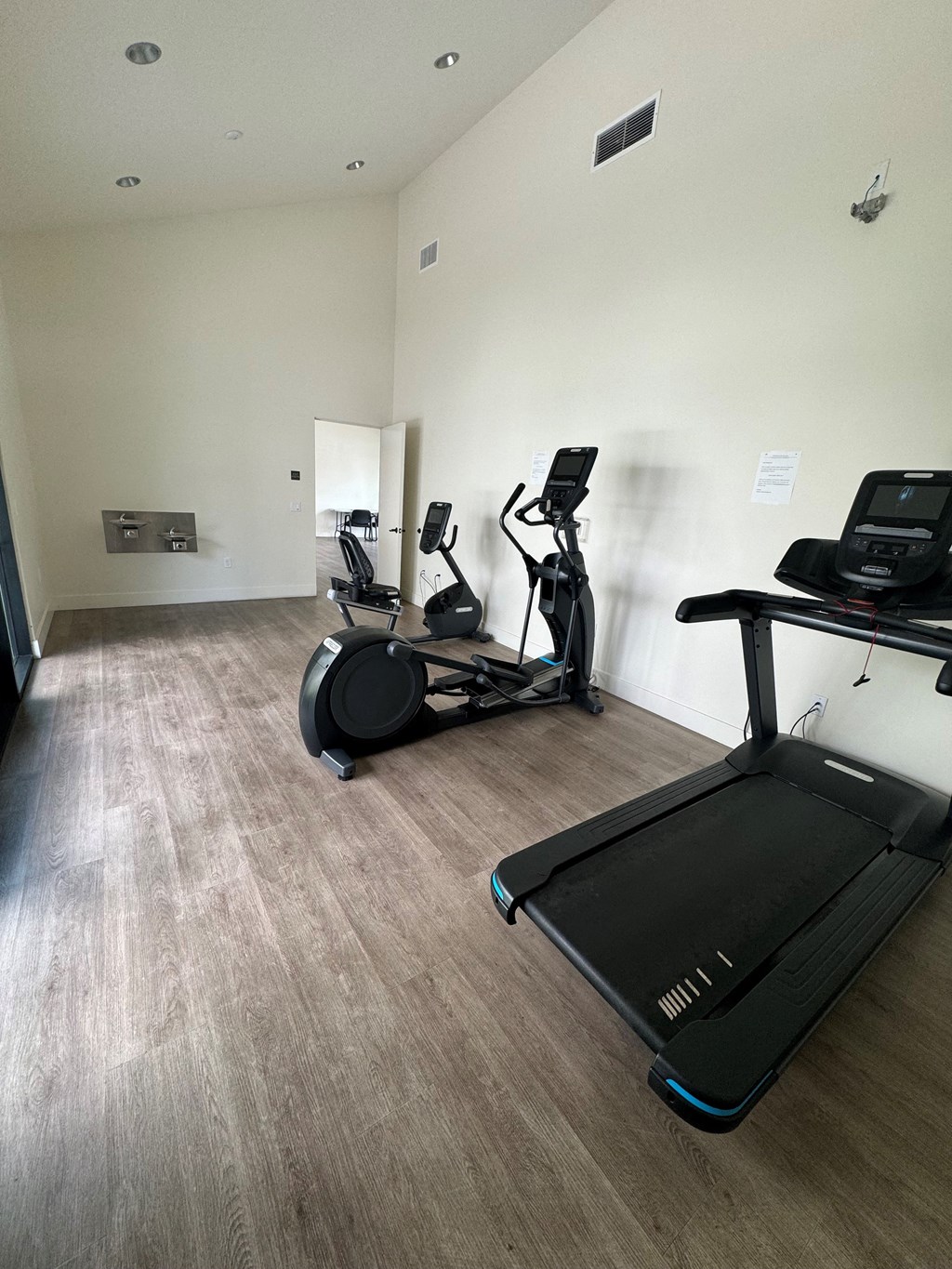a gym with cardio equipment and a wooden floor