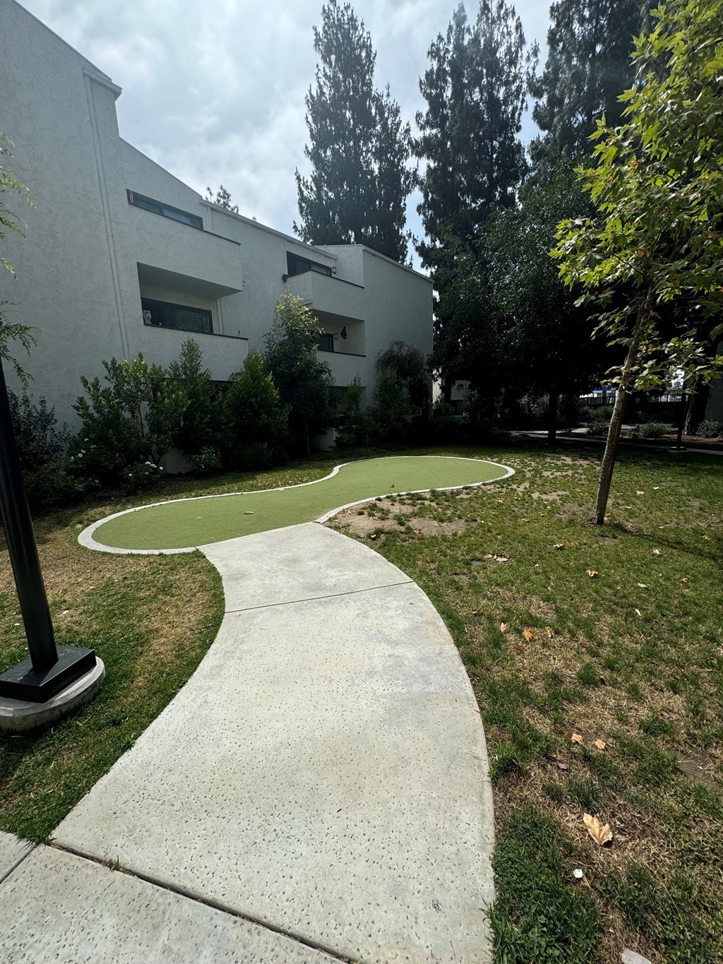a curved sidewalk in front of a building with a golfing area