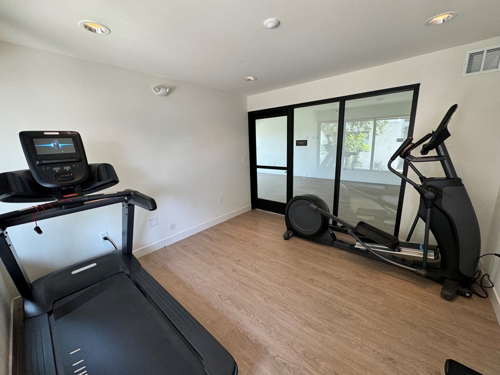 a workout room with mirrors on the wall and a wood floor