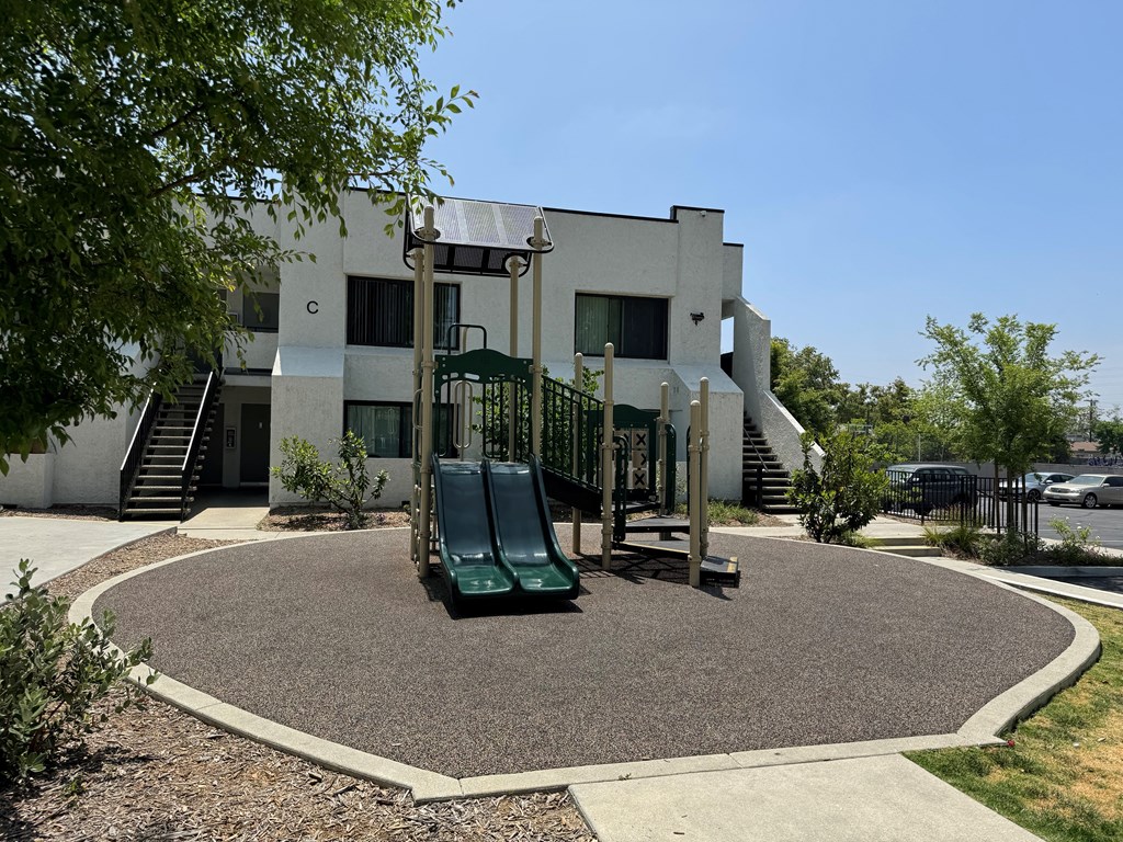 a playground in front of a white building with a slide