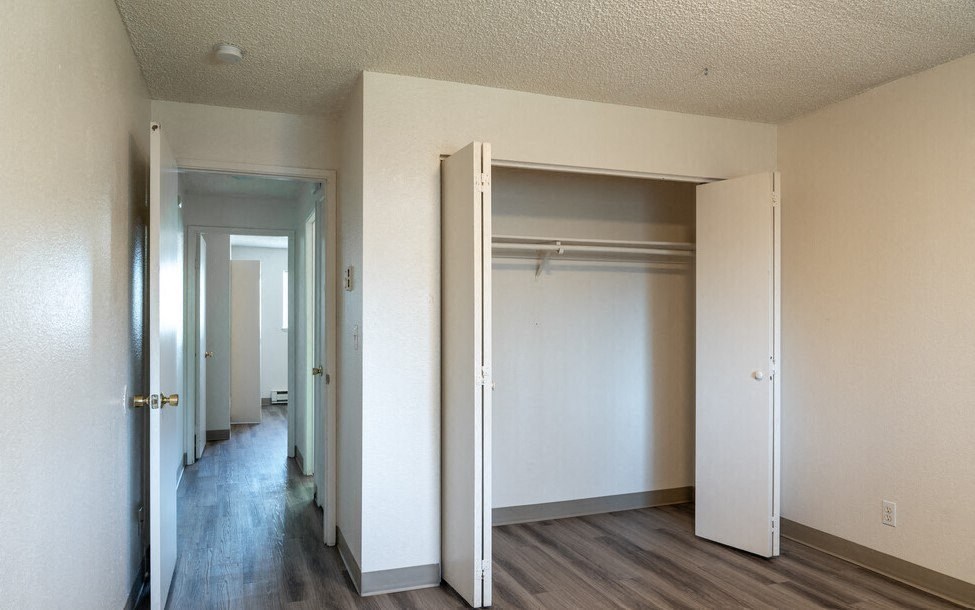 an empty bedroom with a closet and a hallway with doors open