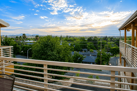 A balcony with a view of a town and trees.