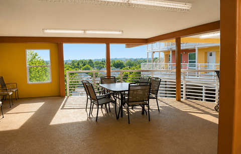 A dining table with chairs is in a room with yellow walls and a view of the outdoors.