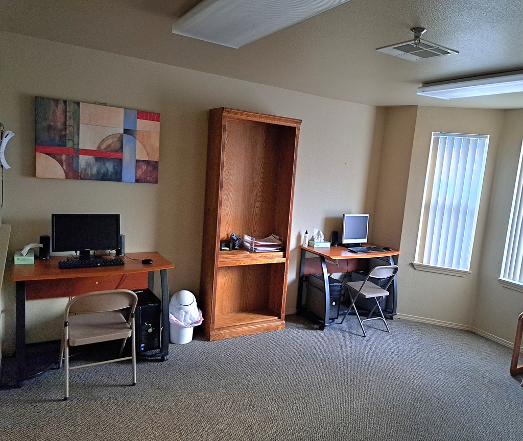 a computer room with two desks and two computer monitors