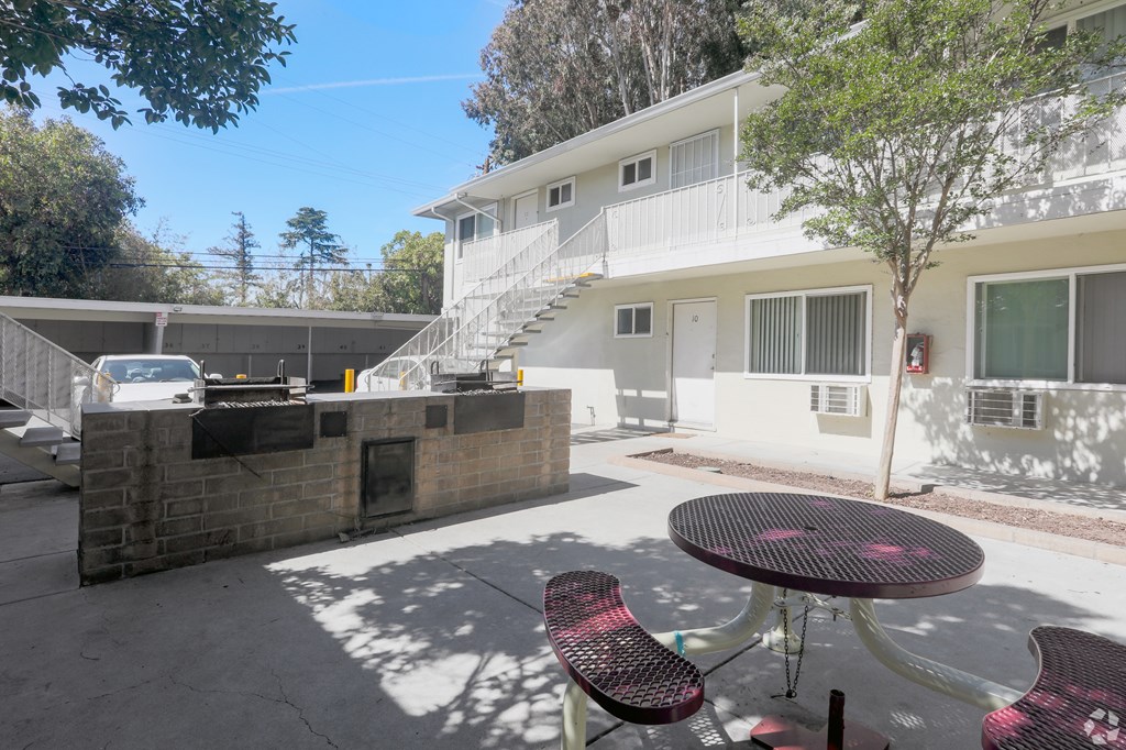 A patio with a table and chairs is in front of a white building.