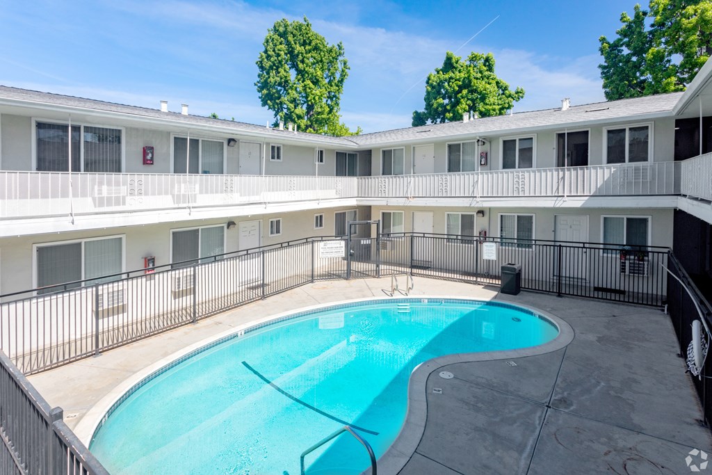 A swimming pool in a courtyard surrounded by a fence.