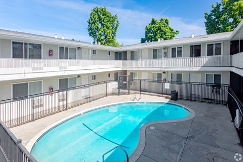 A swimming pool in a courtyard surrounded by a fence.
