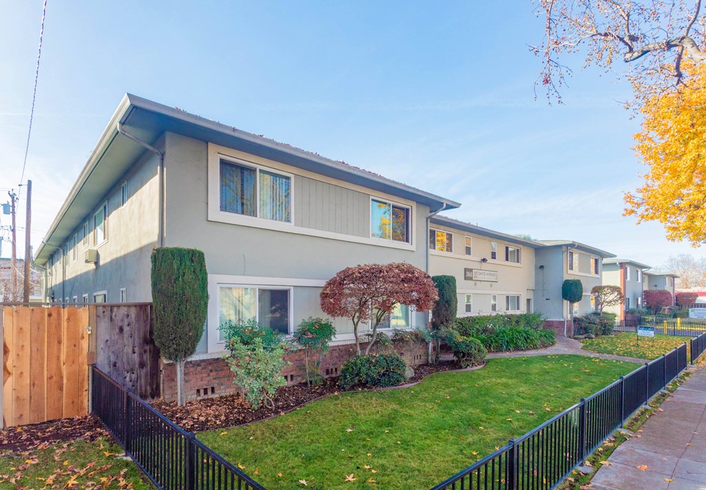 A row of houses with a black fence in front.