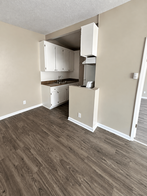 A kitchen with white cabinets and a wooden floor.