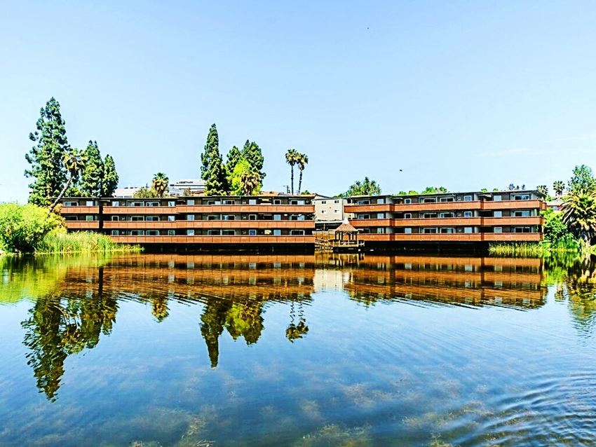 Two apartment buildings 3 story high overlooking a lake.