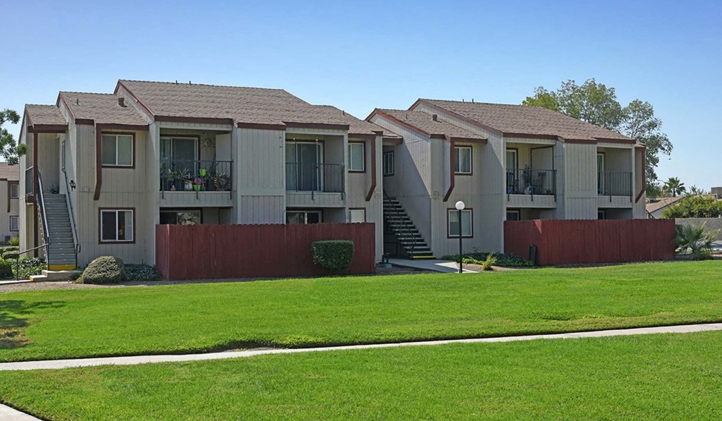 a row of apartments with balconies and green grass