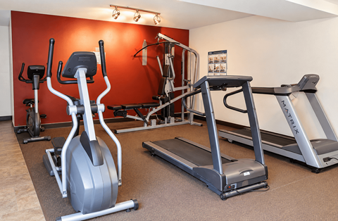 A gym with a red wall and a treadmill.