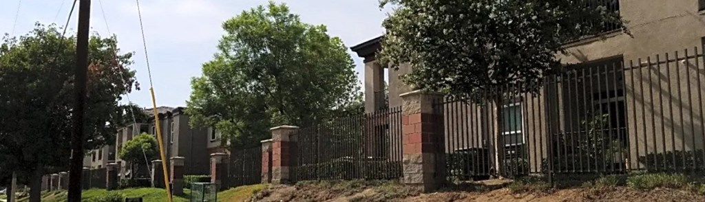 a fence in front of a building with trees in the background