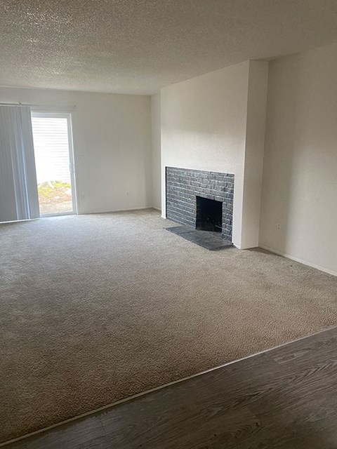 an empty living room with a stone fireplace