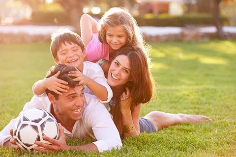 a family lying on the grass with a soccer ball