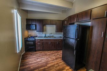 a kitchen with dark wood cabinets and a black refrigerator at The Marquee Apartments, North Hollywood, CA 91605