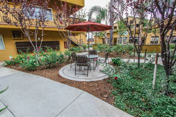 a patio with an umbrella and tables in a courtyard at The Marquee Apartments, California