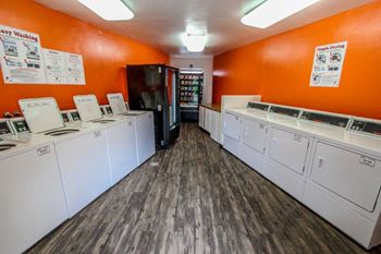 a washer and dryer room with a row of washes and dryers at The Marquee Apartments, California 91605