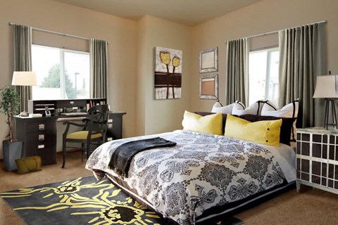 A bedroom with a large bed and a desk with a chair.