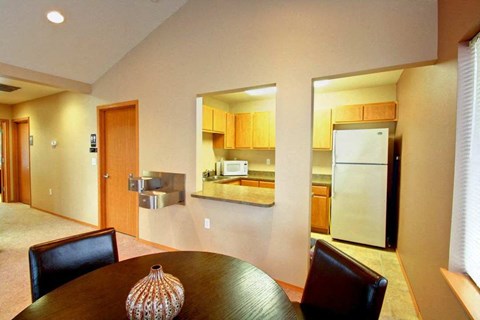 A brown table with a vase on it in a room with a kitchen in the background.