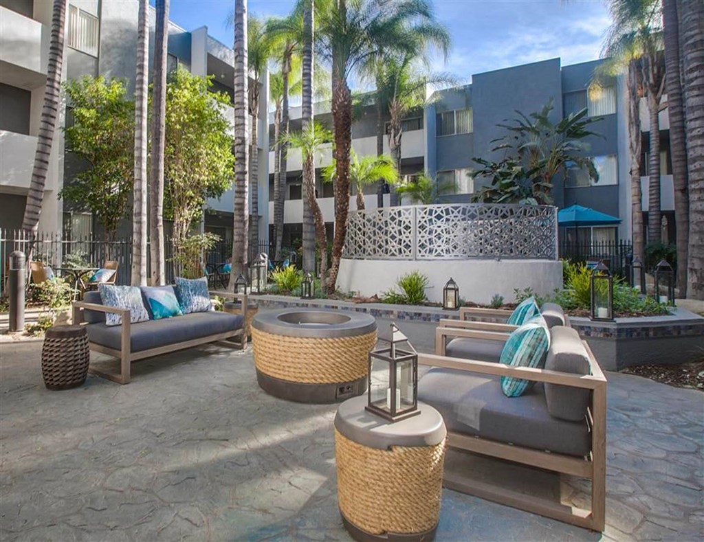 A patio area with wicker furniture and a stone wall.