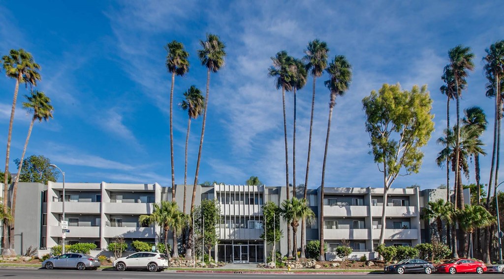 A row of palm trees in front of a building.
