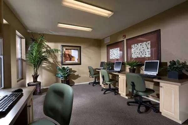 A room with a desk, chairs, and computers.