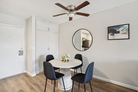 A dining room with a white table and four chairs.