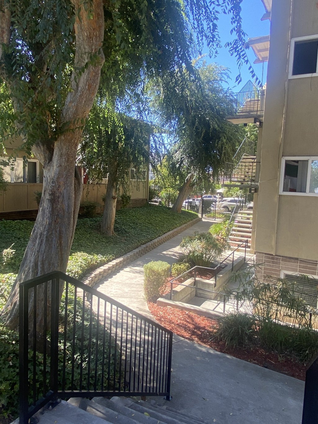an apartment building with stairs and a sidewalk and trees