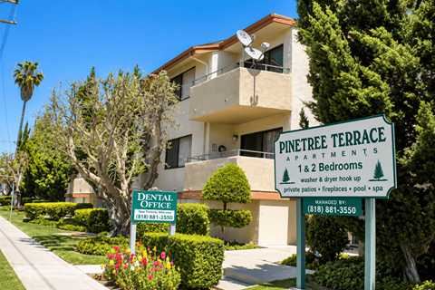A sign for Pinetree Terrace apartments is shown in front of a building.