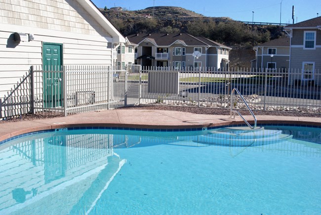 a pool with a fence around it and houses in the background