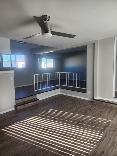 A room with a ceiling fan and wooden flooring.