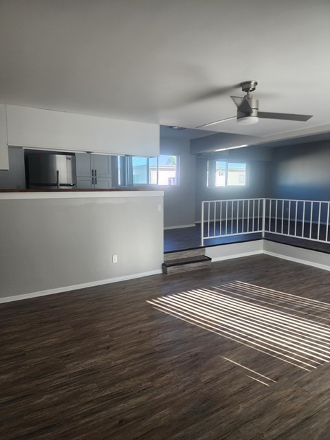 A room with a ceiling fan and wooden flooring.