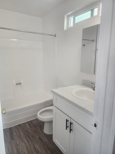 A white bathroom with a toilet, sink, and shower.