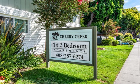 A sign for Cherry Creek 1 & 2 Bedroom Apartments is in front of a building.