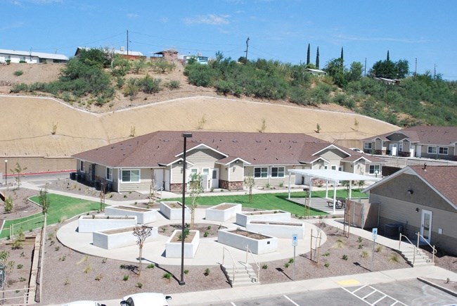 a group of houses on a hillside with a grassy area in front of them