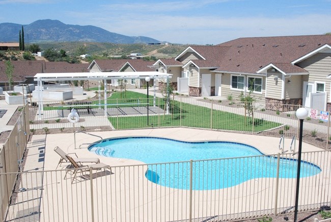 a swimming pool with chairs and umbrellas in front of a house