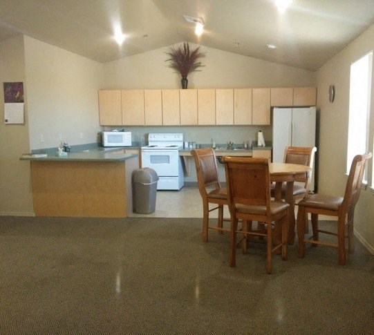 a community room with a kitchen and dining area with a table and chairs