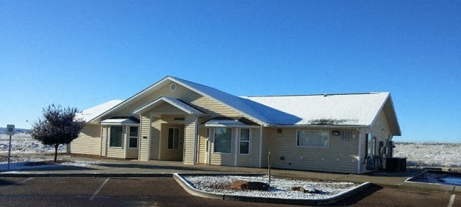 a leasing office building in a parking lot with a blue sky in the background