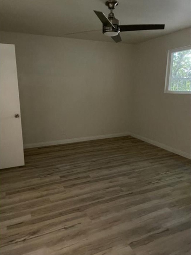 a empty room with wooden floors and a ceiling fan