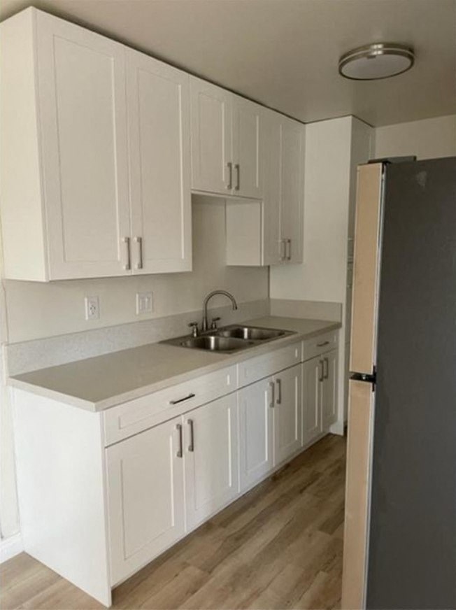 an empty kitchen with white cabinets and a sink