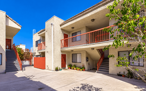 A building with a red railing and a tree in front.