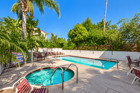 A pool surrounded by chairs and trees.